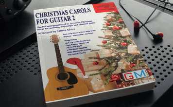 Christmas Carols For Guitar 2 Released By GMI mockup of a paperback book on a dark color metal surface 3416 el1
